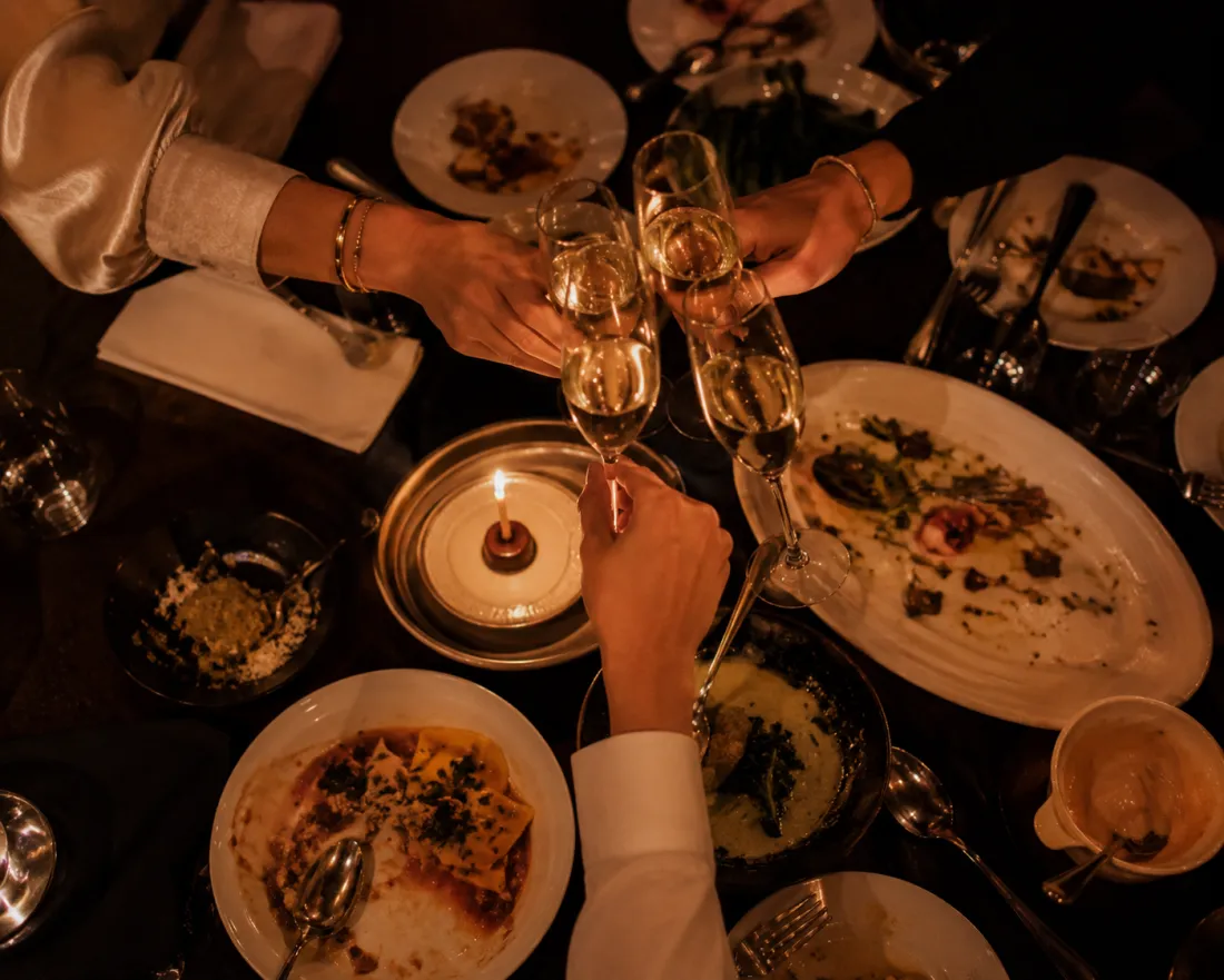 Friends toasting with champagne over a candlelit dinner table